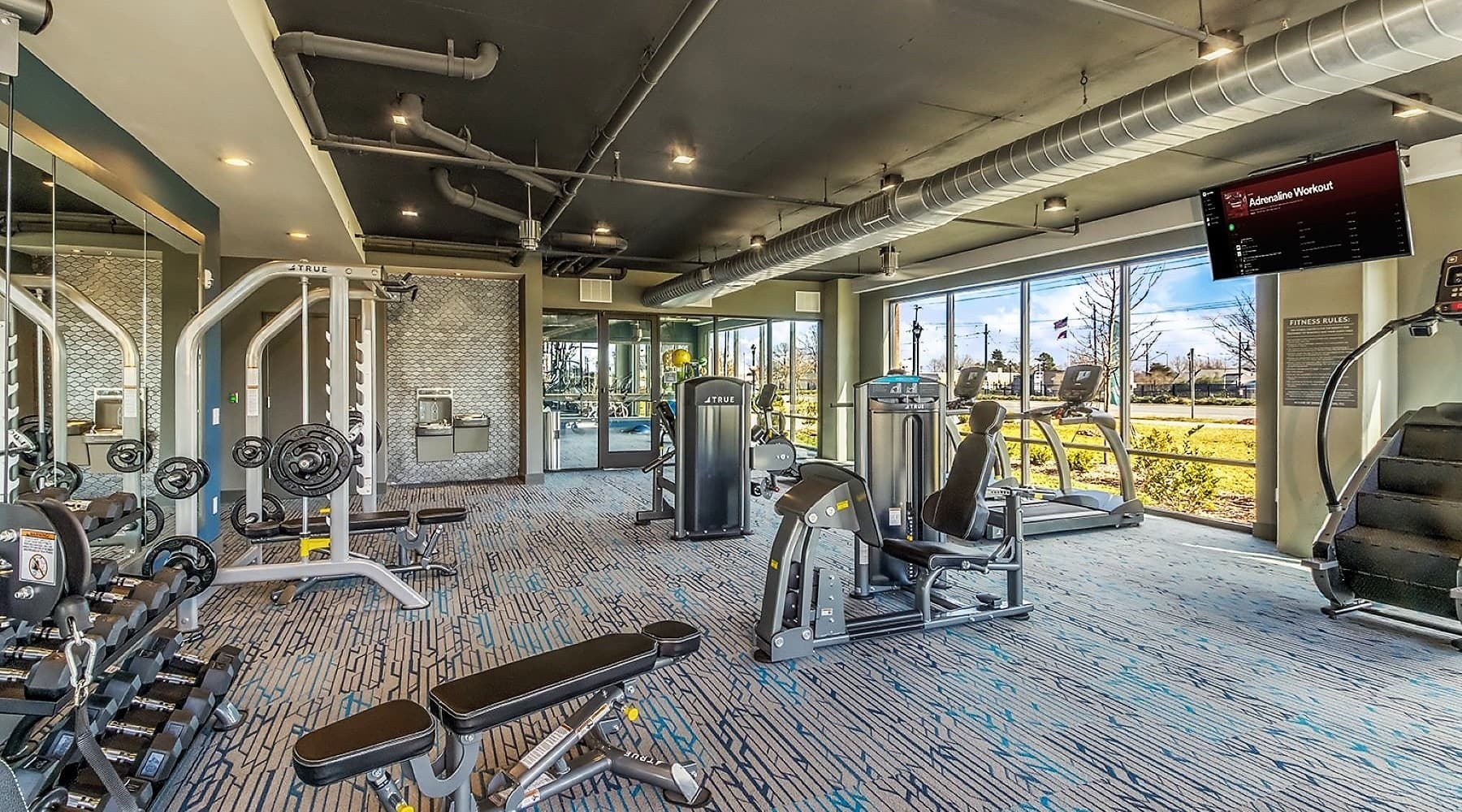 INSPIRED LIVING spacious fitness center with views from wall-to-wall style windows